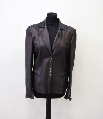 une veste en cuir noir posée sur un mannequin, devant un mur blanc