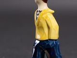 a small figurine of a man wearing a yellow shirt and blue pants