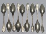 six cuillères en argent sont alignées sur une surface grise