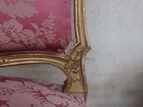 a pink chair with a gold frame and a white wall