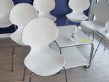 plusieurs chaises blanches et une table dans une pièce aux murs bleus