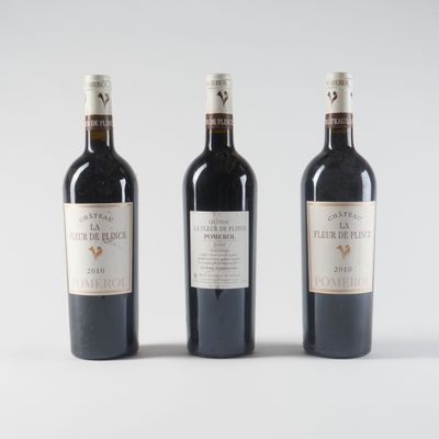 trois bouteilles de vin sont alignées sur une surface blanche