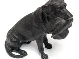 a black dog statue sitting on a white surface