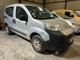 une petite camionnette argentée garée dans un garage avec d'autres voitures