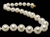 a close up of a white pearl necklace on a black background