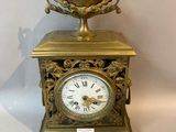 a gold clock sitting on a table next to a silver spoon