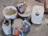 a bucket of cement and a bucket of paint on the ground