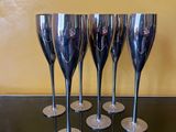 quatre verres à vin argentés posés sur une table en verre