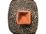 a black and white vase with a red square in the center