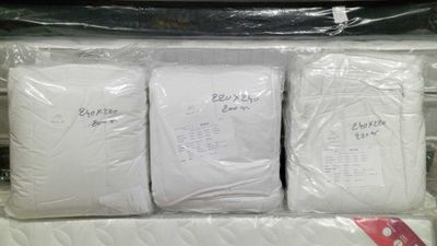 three white pillows in a plastic bag on a shelf