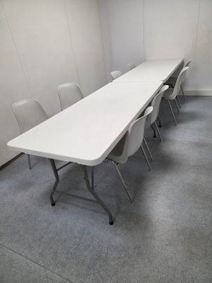 une longue table avec des chaises dans une pièce aux murs blancs
