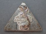 a silver triangle shaped badge with a hammer in it