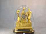 une horloge en or sous un dôme de verre sur une table