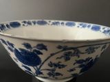 blue and white bowl with flowers on it on a black table