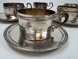 a silver cup and saucer set on a plate