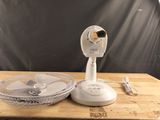 un ventilateur blanc posé sur une table, à côté d'un bol de nourriture