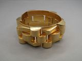 un bracelet en or posé sur une table, sur fond gris