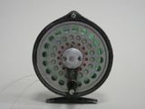 a close up of a fly fishing reel on a white surface