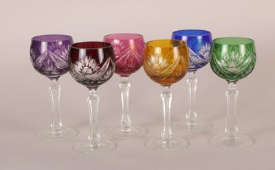 six verres à vin de couleurs différentes sont alignés sur une surface blanche