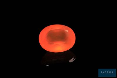 une pierre orange vif sur une surface noire