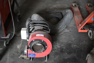 un ventilateur rouge posé par terre à côté d'une machine rouge