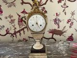 a clock sitting on a marble table next to a lamp