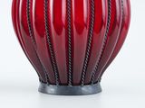 a close up of a red vase on a white surface