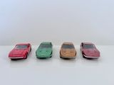 quatre petites voitures sont alignées sur une surface blanche