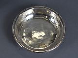 a silver bowl on a table with a black background