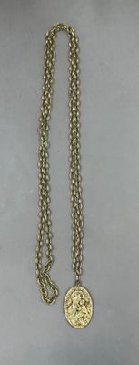 collier plaqué or avec une pièce de monnaie suspendue à une chaîne, posé sur une table
