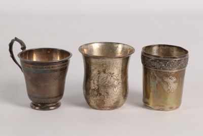 three silver cups are lined up next to each other on a white surface