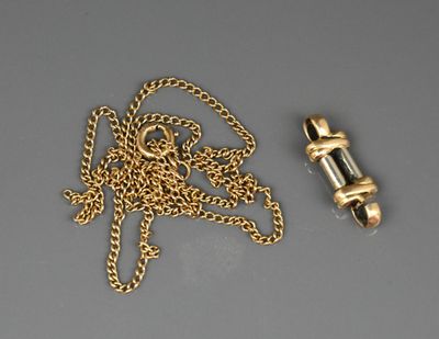 une photo représentant une chaîne en or et un briquet posés sur une table