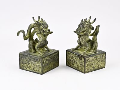 une paire de serre-livres anciens en bronze représentant des dragons, sur fond blanc