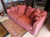 a pink couch sitting in a living room next to a coffee table