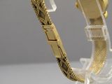 une montre en or posée sur un socle transparent, sur une table
