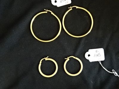 trois paires de boucles d'oreilles créoles en or sur fond noir