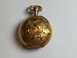 a gold pocket watch on a white surface