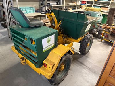 un camion-benne vert et jaune garé dans un garage