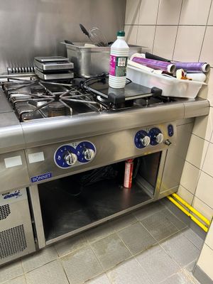 une plaque de cuisson en acier inoxydable dans une cuisine, sur laquelle sont posées des casseroles et des poêles