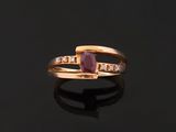 a close up of a gold ring with a ruby stone and diamonds