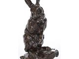 une statue en bronze représentant un lapin assis sur un rocher