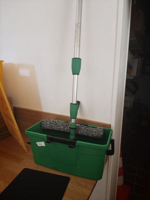 a mop that is sitting on the floor next to a green bucket