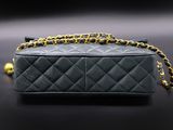 a black chanel bag with gold chain on a black background