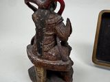 a small statue of a man sitting on a bench next to a small chalk board