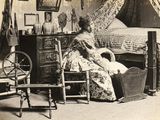 une femme assise sur une chaise devant un lit