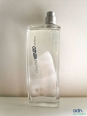 un flacon de parfum posé sur une surface blanche, avec un fond blanc