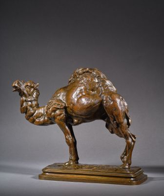 une statue en bronze représentant un chameau, posée sur un socle en bois
