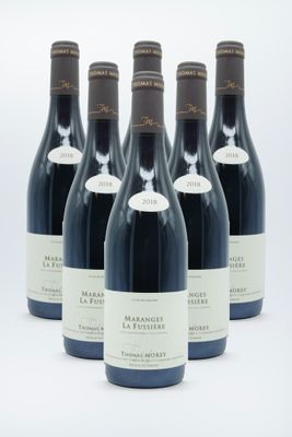 six bottles of wine are lined up in a row on a white surface