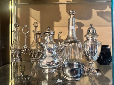 a lot of silver items on a glass shelf