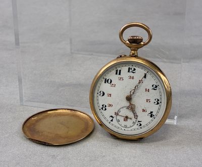 a gold pocket watch sitting next to a glass container